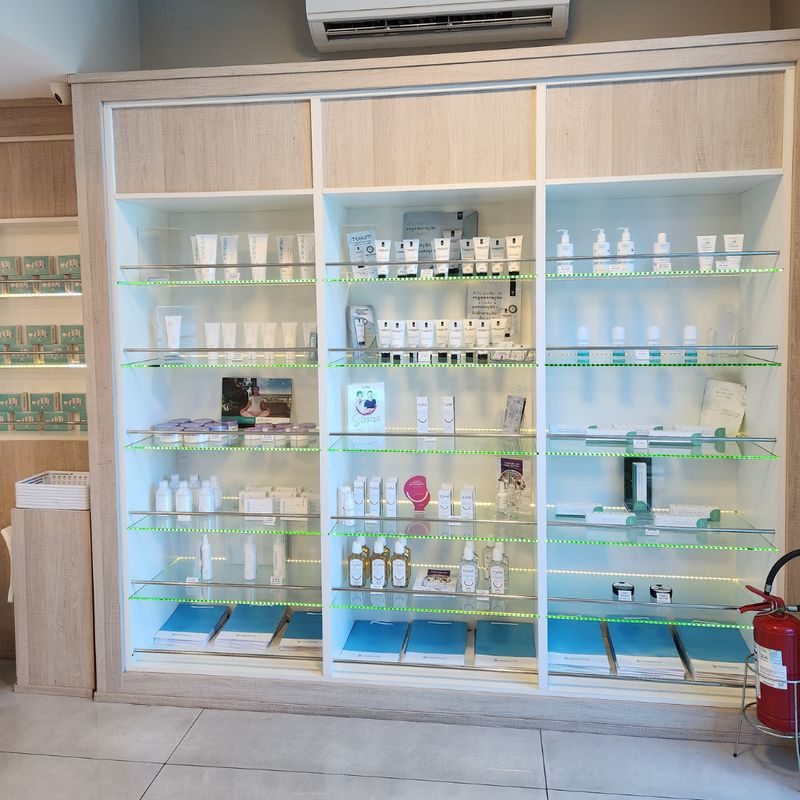 Ampliar foto: expositor iluminado com dermocosméticos em prateleiras de vidro.